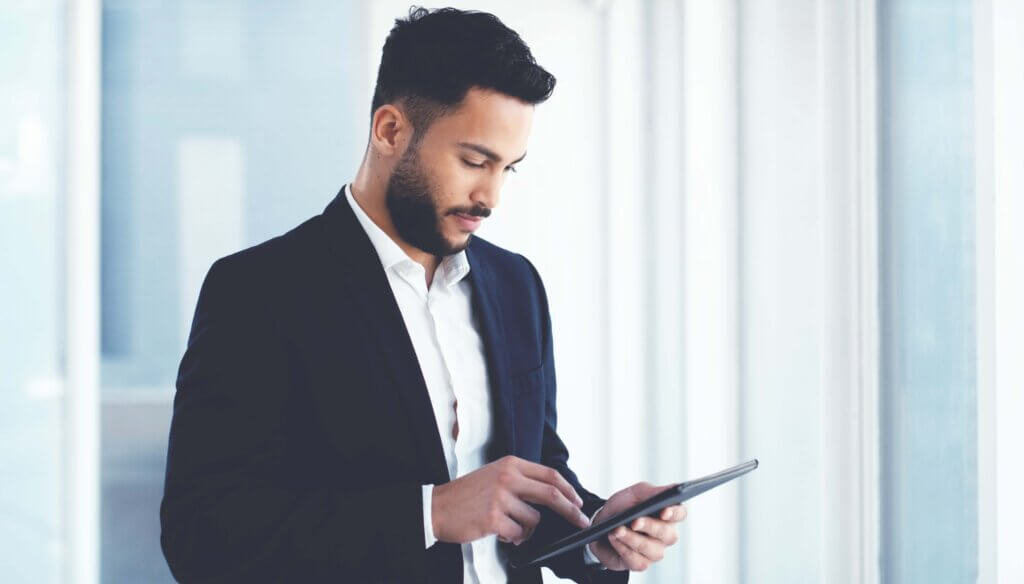 technology man smiling looking at screen standing up scaled
